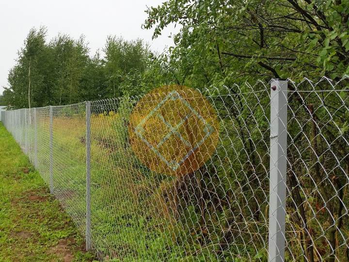 забор из сетки рабицы с серыми опорными столбами