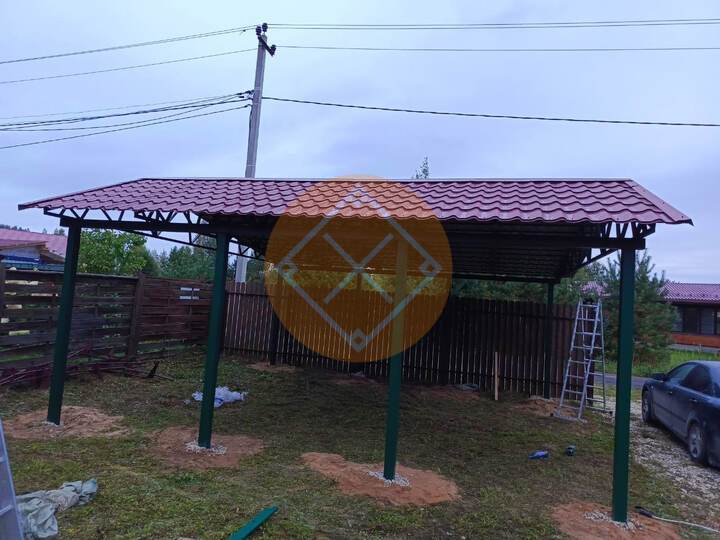 зеленый металлический навес с двускатной кровлей из красной металлочерепицы
